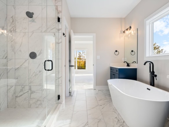 Elegant bathroom featuring a freestanding bathtub, marble tiled walls, and contemporary fixtures.