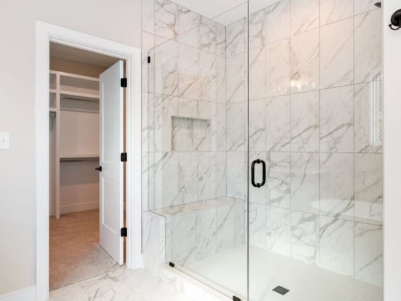 Modern marble shower with glass enclosure in a new home.