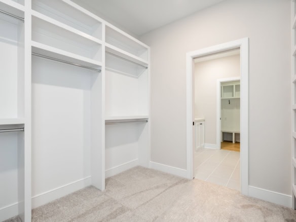 Spacious walk-in closet with white shelving and neutral decor.
