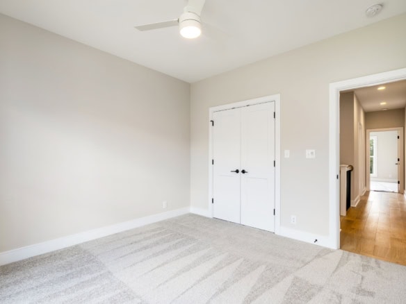 Bright, spacious bedroom with neutral walls and plush carpet flooring.