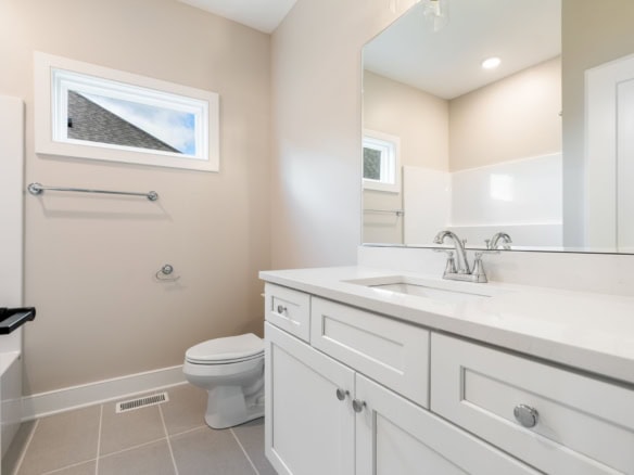 Bright, clean bathroom with white cabinetry and a large mirror.
