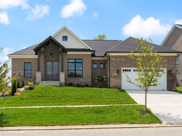 Beautiful new construction home with brick and siding exterior, large windows, and a spacious front.
