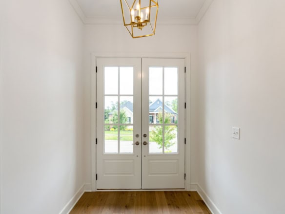 Bright white entry door with glass panels and view of neighborhood outside.