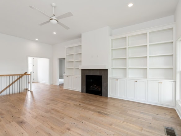 Bright living room with white built-in shelves and a fireplace, featuring hardwood floors and large.