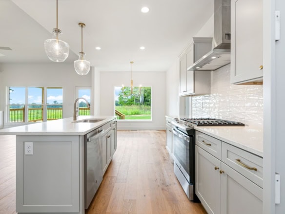 Bright, spacious kitchen featuring white cabinets, stainless steel appliances, and large windows.