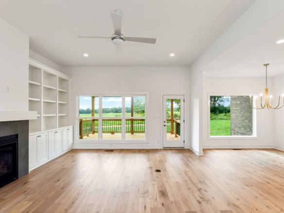 Bright living room with large windows overlooking a green landscape, featuring hardwood floors and a.