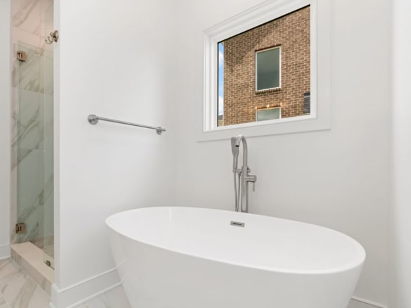 Modern bathroom with a freestanding tub and large window.