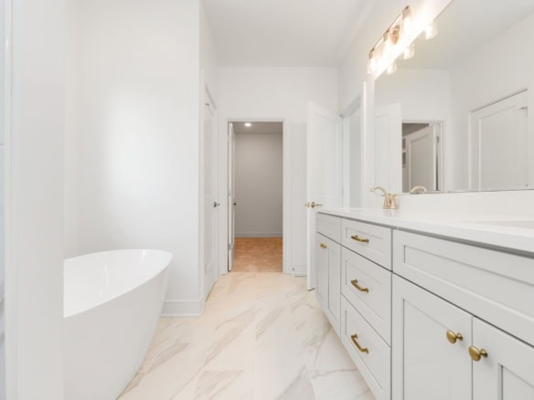 Bright modern bathroom featuring white cabinetry and a freestanding bathtub.