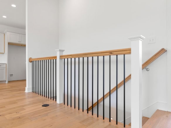 Staircase railing with black metal balusters and wooden handrail at 3236 Catalpa Farms Dr.