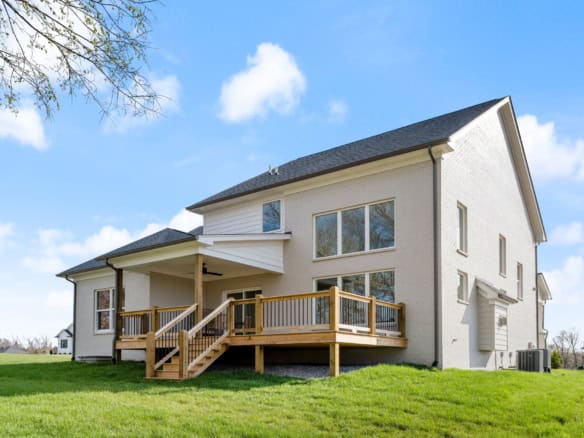White house with a spacious wooden deck and large windows.