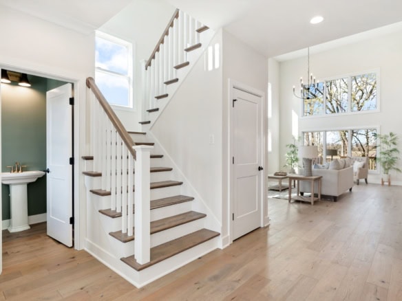 Staircase with white risers and wooden handrail in a spacious, well-lit home.
