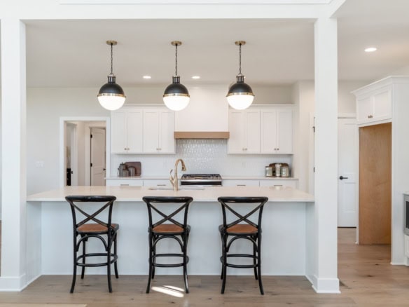 White kitchen with island and three pendant lights.