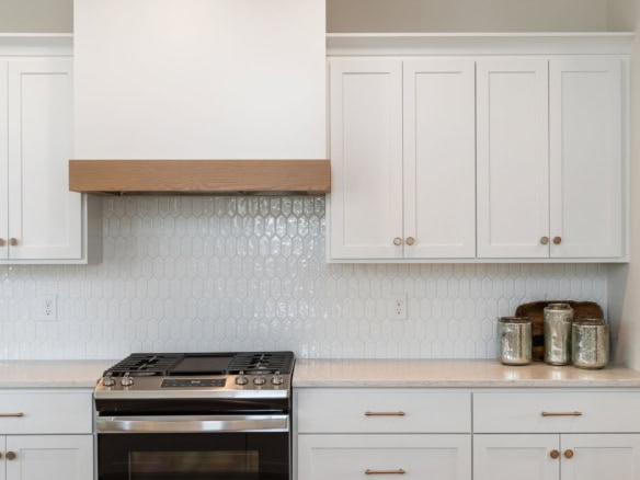 Modern kitchen with white cabinets and stainless steel stove.