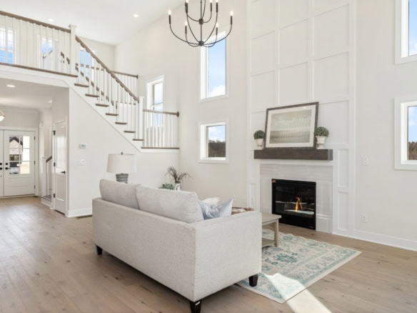 Spacious living room featuring a cozy fireplace, high ceilings, and abundant natural light from larg.