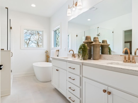 Bathroom with white cabinetry and gold fixtures.