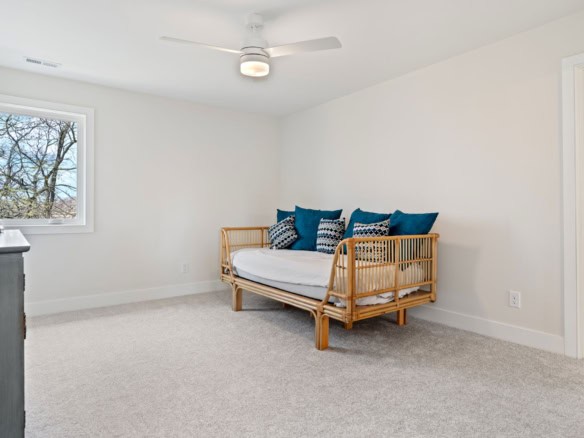 Modern bedroom with white walls, ceiling fan, and cozy seating area.