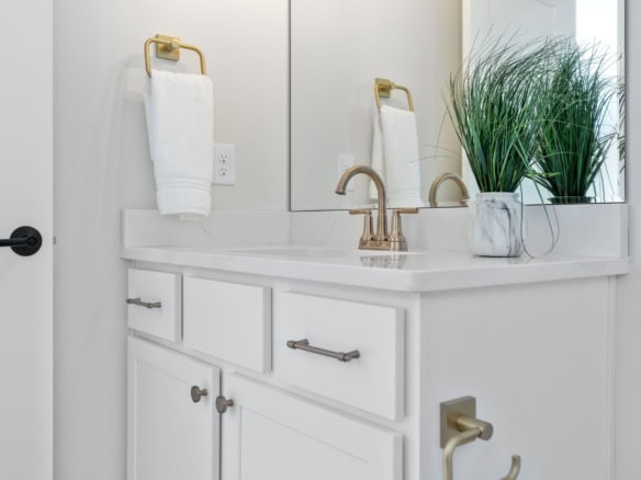 Modern bathroom vanity with white cabinets and gold fixtures.