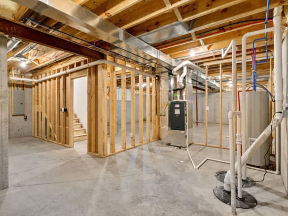 Interior view of a new basement framing and utility installation under construction.