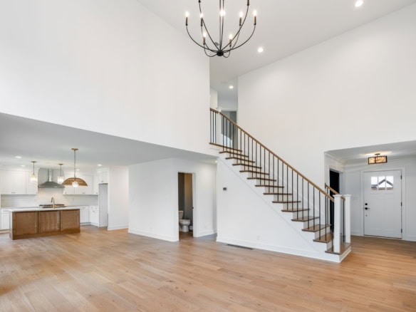 Spacious living area with high ceilings, hardwood floors, and a stylish staircase.