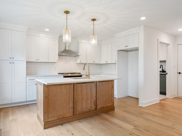 Modern white kitchen with a central wooden island and pendant lighting.