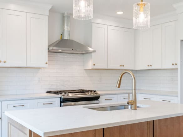 Modern white kitchen with gold fixtures and sleek design.