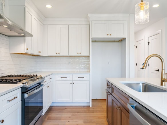Bright modern kitchen featuring white cabinets, gold hardware, and a spacious island.