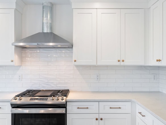 Bright white kitchen with stainless steel stove and white cabinetry.