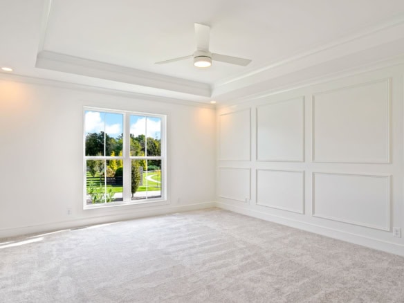 Interior view of a spacious, bright living room with large windows and elegant white wall paneling.