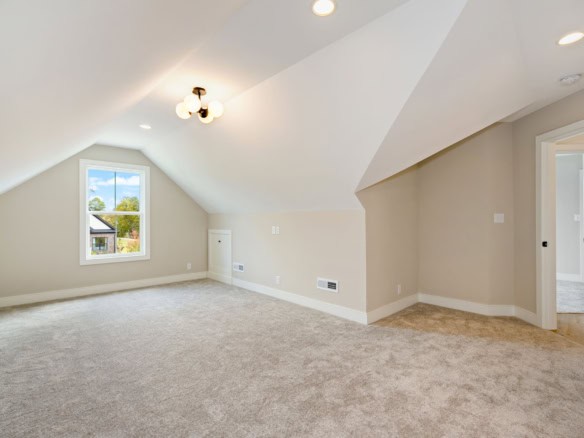 Spacious, bright attic room with large window and neutral decor, perfect for versatile living space.