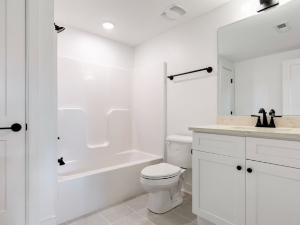 Bathroom with white tiles, bathtub, and vanity in a new construction home.