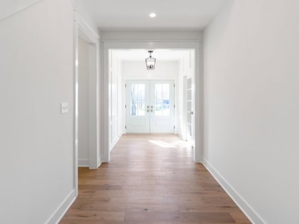 Interior entryway with white walls, hardwood floors, and natural light.