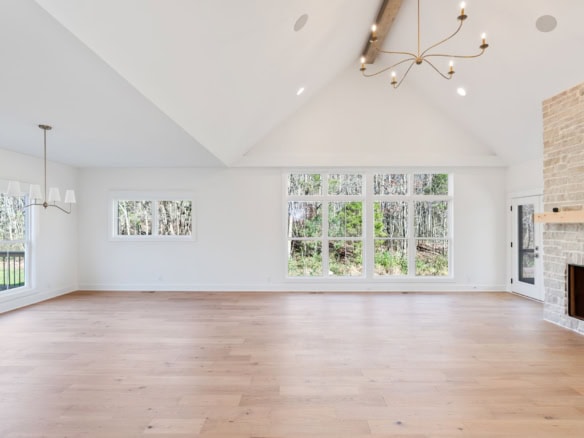Spacious interior with bright natural light, white walls, and hardwood flooring in a newly built hom.