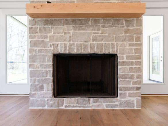 Fireplace with stone surround and wooden mantel in a contemporary living space.