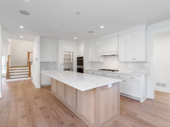 Modern white kitchen with island and stainless steel appliances.