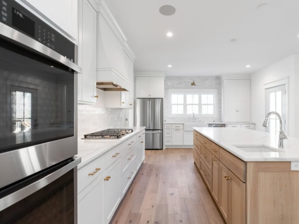Spacious kitchen featuring white cabinetry, a central wooden island, and stainless steel appliances.