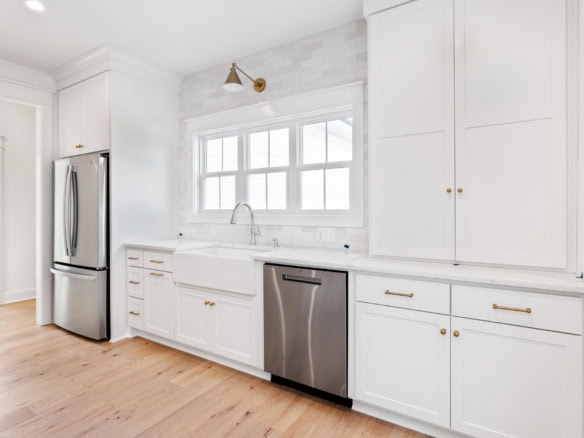 White kitchen with stainless steel appliances and large window.