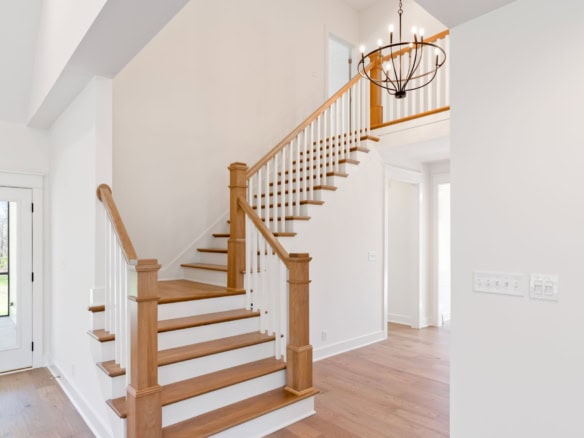 Staircase with wooden handrails and white risers in a bright, open home interior.