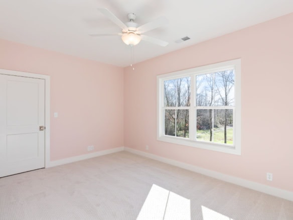 Bedroom interior with pink walls and large window overlooking the yard.