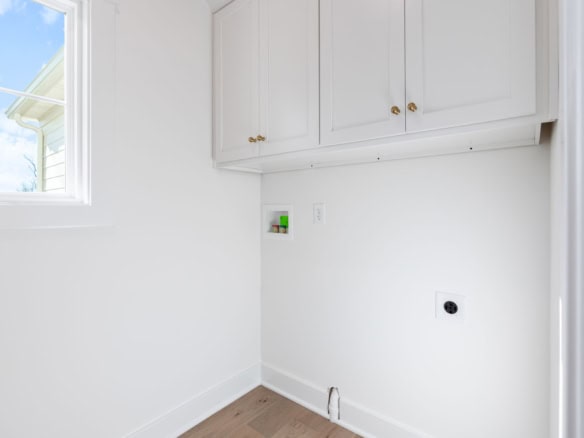 Modern laundry room with white cabinets and natural light.