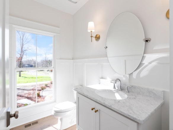 Bathroom with white walls, marble countertop, and large window overlooking a garden.