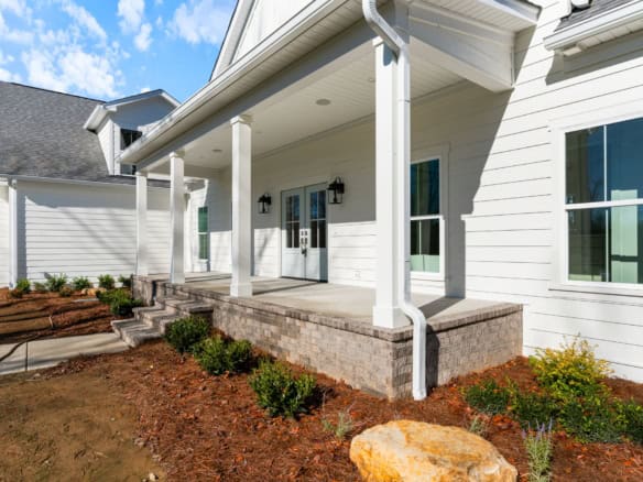 Modern white house with a welcoming front porch and landscaped yard.