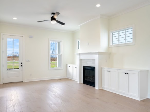 Bright living room featuring a cozy fireplace, large windows, and white cabinetry, perfect for comfo.