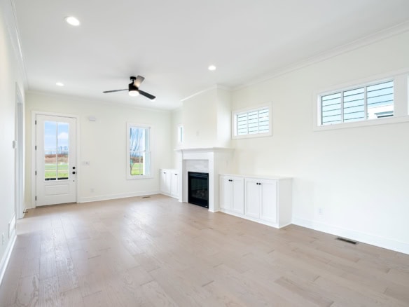 Modern living room with white walls, large windows, and a fireplace. Bright, spacious, and perfect f.