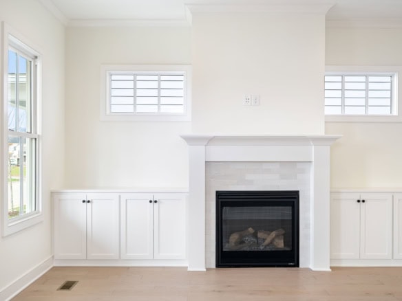 Fireplace with white mantel and built-in cabinets in a bright living room.