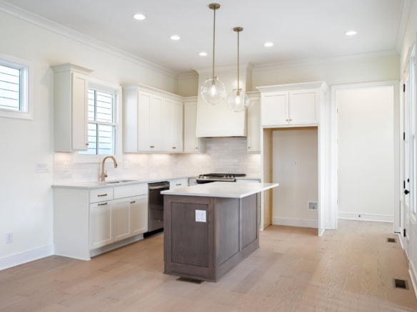 Modern white kitchen with island, bright natural light, and contemporary design at 6111 Passionflowe.