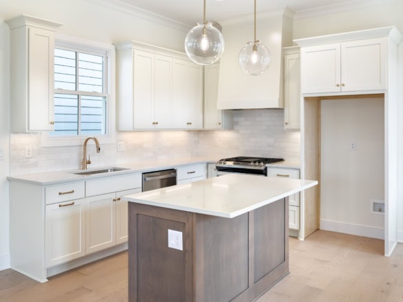 Modern white kitchen with island, cabinetry, and pendant lights at 6111 Passionflower Dr.