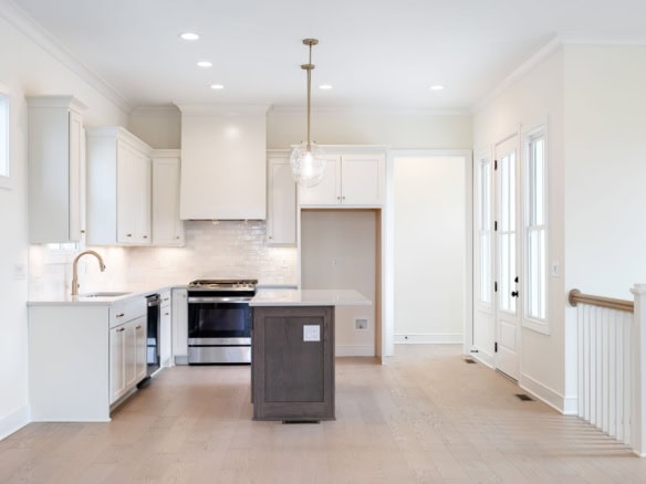 Modern white kitchen with island, bright natural light, and sleek cabinetry at 6111 Passionflower Dr.