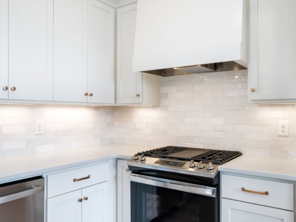 Modern white kitchen with stainless steel stove and cabinetry at 6111 Passionflower Dr.