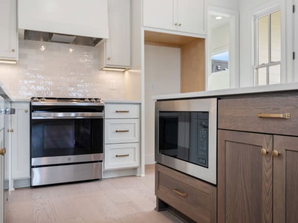 Bright kitchen featuring white cabinetry, a stainless steel stove, and a cozy island.
