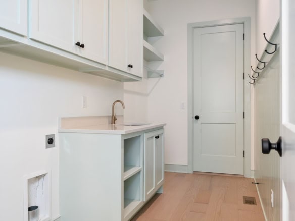 Laundry room with white cabinets and beige countertop at 6111 Passionflower Dr.